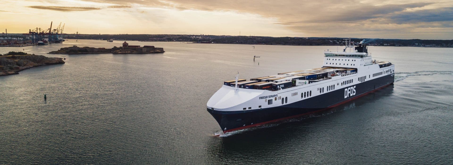 Photo of a DFDS Freesia Seaways freight ship at sea in the morning dawn