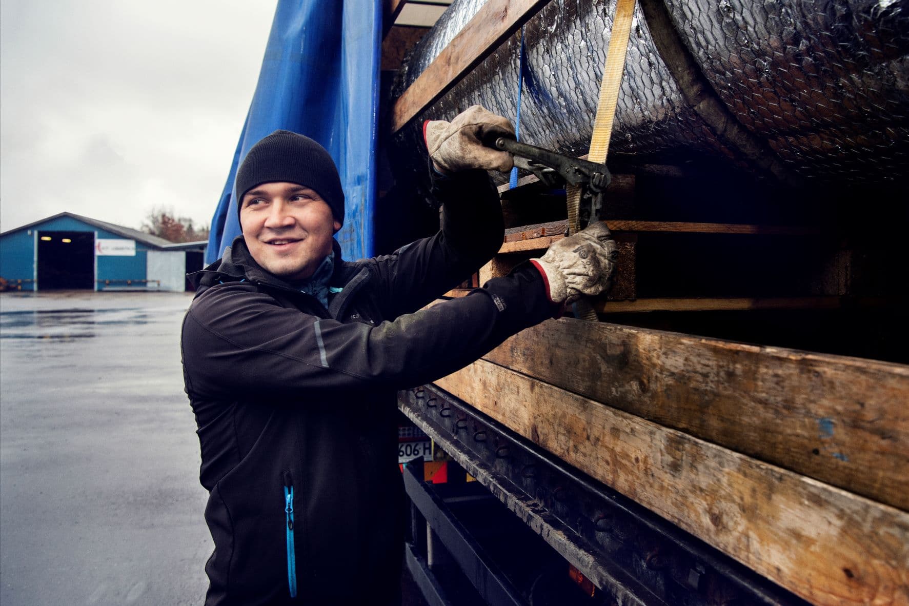DFDS-lastbilschaufför som surrar fast last på en trailer.