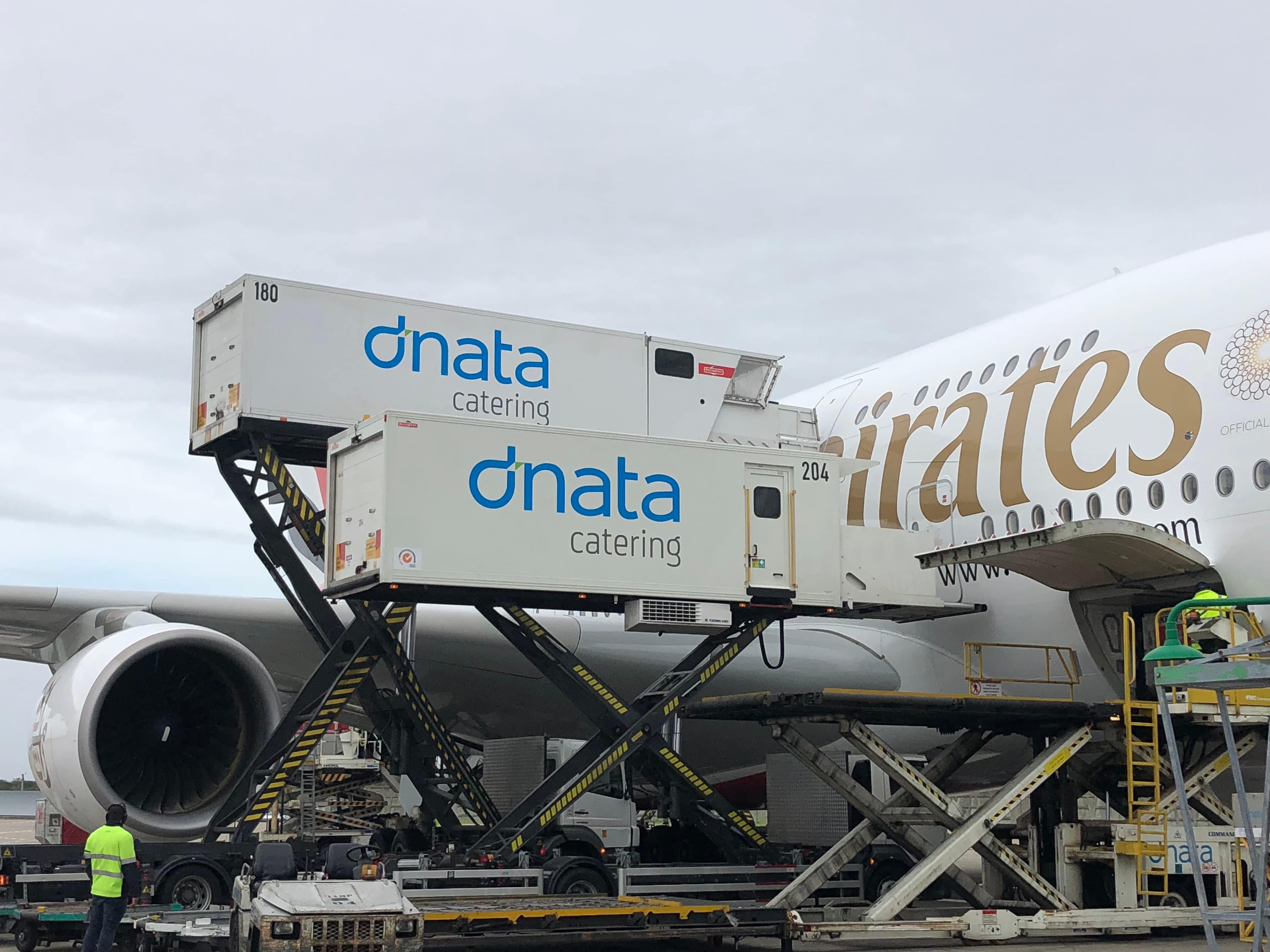 Dnata trailers in front of an emirates plane.